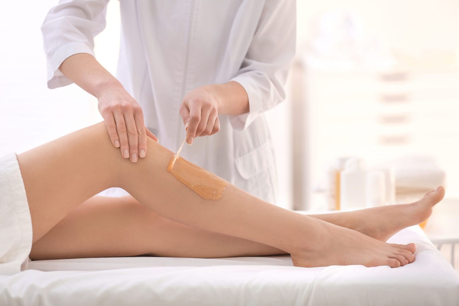 A therapist applying warm wax to a client’s lower leg.